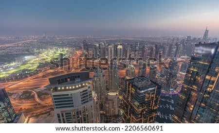 Panorama of Dubai Marina with JLT skyscrapers and golf course day to night transition timelapse, Dubai, United Arab Emirates. Aerial view from above towers after sunset