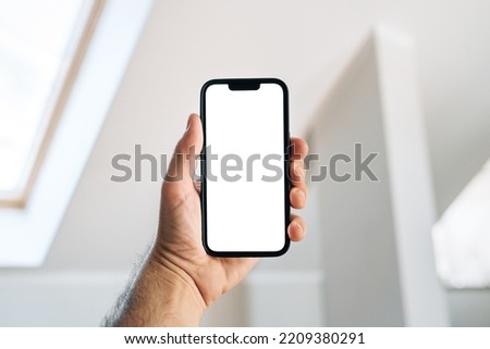 Tourist in hotel room holding smartphone with blank mockup screen for booking and reservation app or accommodation rating service