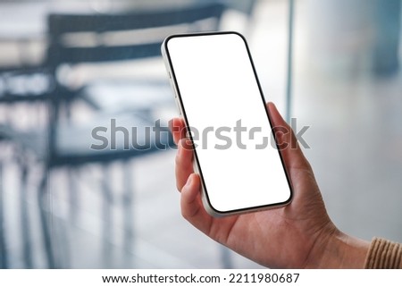 Mockup image of a woman holding mobile phone with blank desktop screen