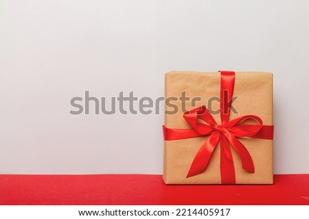 holiday brown paper present tied red ribbon bow top view with copy space. Flat lay holiday background. Birthday or christmas present. Christmas gift box concept with copy space.