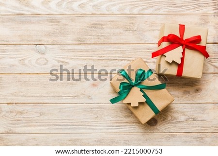 wrapped christmas or other holiday handmade present in paper with colored ribbon. Present box, decoration of gift on colourfull table, top view with copy space.