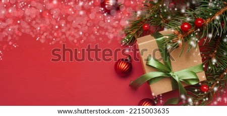    Spruce, fir branches, red berries, gift box on red background. Frame border. Christmas composition, greeting card. Space for text. Banner.                               