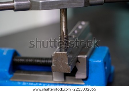 Spiral fluted steel tap bit making a thread in hole on mounted vise,Tapping the workpiece,machine vise