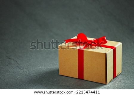 Packed gift box tied with a red ribbon with a bow on dark background Studio shot from a high angle. With copy space.