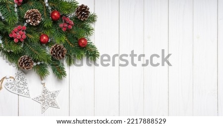 Christmas tree branch decorated with red balls and fir cones on white wooden background. Top view, flat lay with copy space, banner, header, New Year background