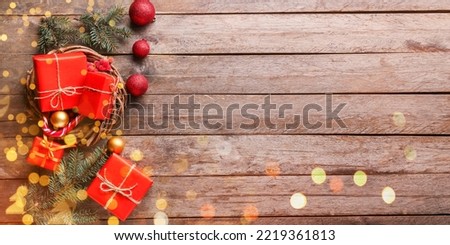 Christmas gifts with fir branches and balls on wooden background with space for text, top view