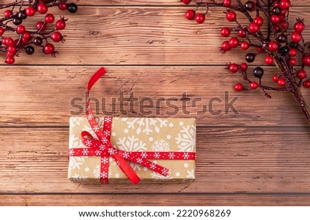 Christmas present wrapped with red bow on a decorated wooden table