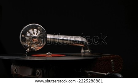 Vintage old record player gramophone needle on vinyl record. Round shiny metal needle holder head reproducing music. Retro vintage vinyl player on black background. Needle old gramophone close up.