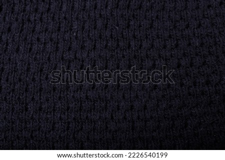 Knit black fabric texture, background or backdrop. Textile, scarf or sweater textured surface. Warm accessories, clothing, fashion concept.