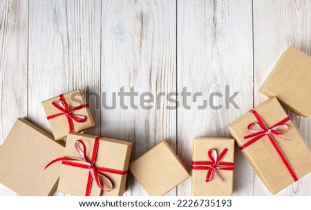 craft boxes tied with red ribbons lie on a white wooden background, copy space