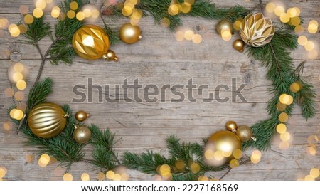 Christmas advent celebration holiday background greeting card - Frame made of pine branches, golden christmas baubles balls and bokeh lights on rustic wooden table texture top view