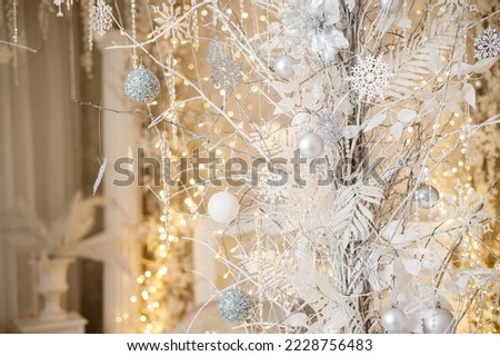 A white Christmas tree is decorated with silver plastic toys. Bright festive decoration for the new year