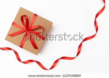 Craft present box with red bow and red ribbon on the white background