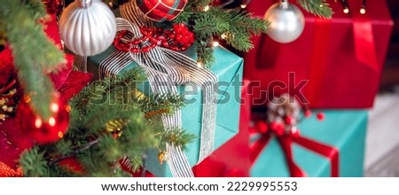 Closeup gift box with bowknot on blurred background red decorated christmas tree pine bokeh sun light banner.