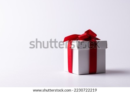 White gift box tied with red ribbon, on white background with copy space. Valentine's day, love, romance and celebration concept.