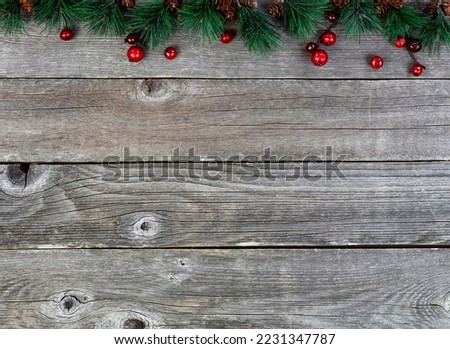 Merry Christmas or happy New Year background with fir tip tree branches and red berries on rustic wood boards 