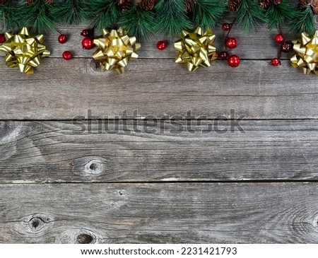Merry Christmas or happy New Year background with fir tip tree branches and gold bows on rustic wood boards 