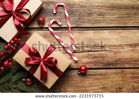 Gift boxes, candy canes and Christmas decor on wooden table, flat lay. Space for text
