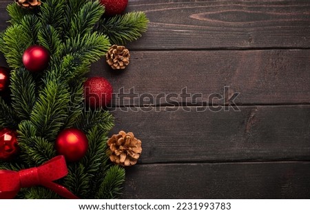 Christmas decorations with fir branches, Christmas balls and cones on brown wooden boards, top view with copy space