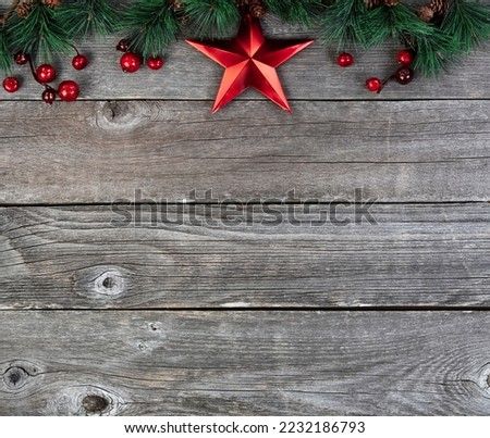 Merry Christmas or happy New Year background with fir tip branches and red star decoration on rustic wood boards 