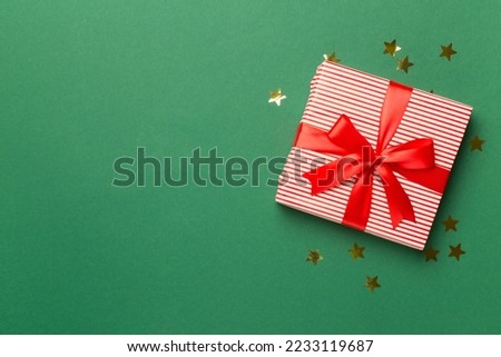 Gift box and stars confetti on color background, top view?