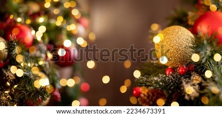 Close-up of red and gold decorations on a Christmas tree. New Year's brown background with lights and space for text