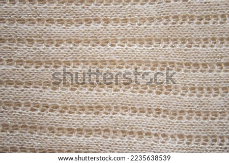 Soft beige knitted fabric as background, closeup. Openwork knitting, horizontal direction. Copy space for text. Design for text. Directly Above View