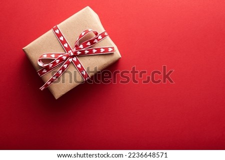 Top view photo of saint valentine's day decorations glowing sequins and craft paper giftbox with red ribbon bow on isolated red background with copyspace