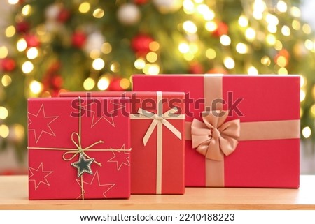 Beautiful gifts on table against blurred Christmas tree