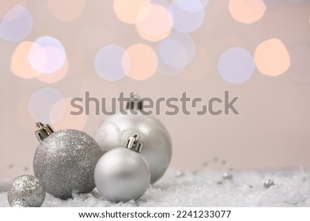Silver Christmas balls on snow against blurred lights