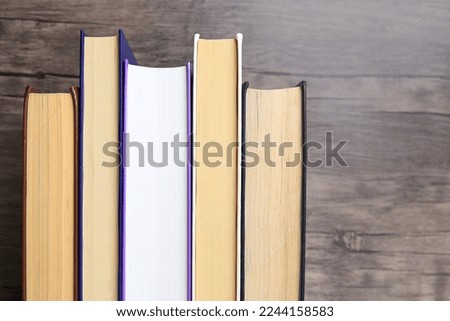 Collection of different books near wooden wall, closeup. Space for text