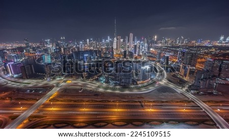 Panoramic skyline of Dubai with business bay and downtown district night. Aerial view of many modern skyscrapers. Bridges over highway. United Arab Emirates.