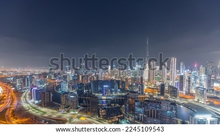 Panoramic skyline of Dubai with business bay canal and downtown district night timelapse. Aerial view of many modern skyscrapers. United Arab Emirates.