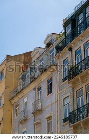 A vertical shot of a beautiful building with balconies and windows against a clear blue sky in Lisbon