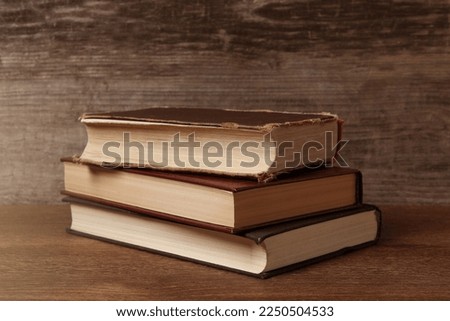 Stack of old hardcover books on wooden table