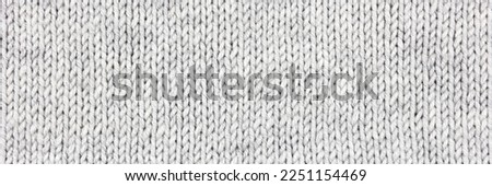 Knitted gray background. Large knitted fabric with a pattern. Close-up of a knitted blanket. Horizontal ornament. Banner