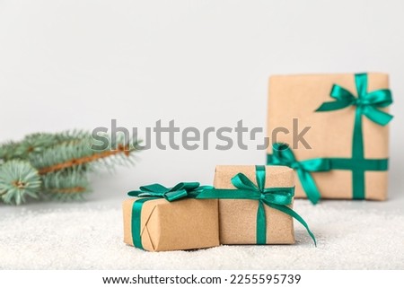 Beautiful gift boxes tied with green ribbon and snow on white background