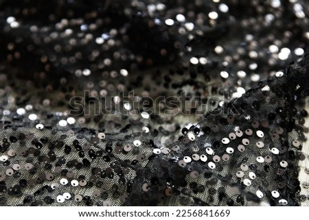 defocused black and silver knitted fabric with sequins and folds texture background	