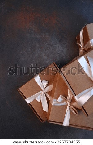 Gift delivery. The cardboard holiday box is tied with a ribbon. Festive packaging. A gift for the holiday. With a space to copy. View from above. Dark background.Vertical photo.