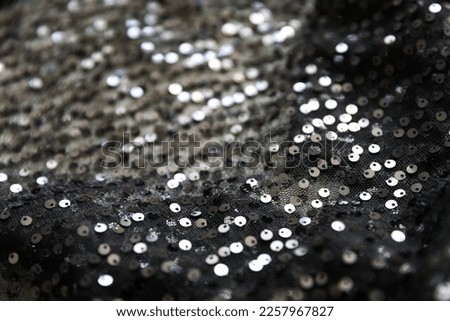 defocused black and silver knitted fabric with sequins and folds texture background	
