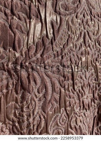 Close-up of gold elements on muted pink brocade fabric
