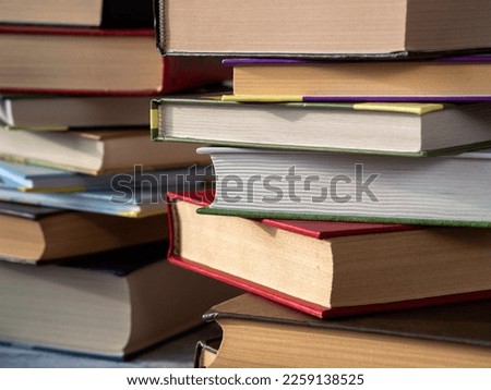Books of various thicknesses and with various covers are stacked. Close-up. Background for libraries, education, scientific work.