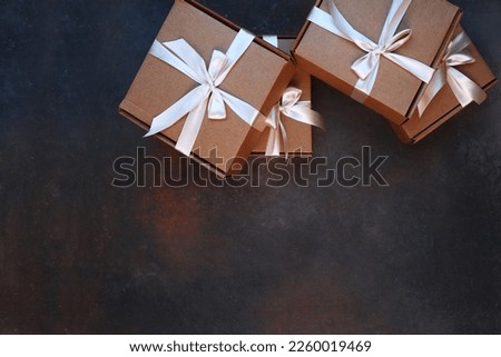 The cardboard holiday box is tied with a ribbon. Holiday gift wrapping. A gift for the holiday. With a space to copy. Gift delivery. View from above. Dark background.