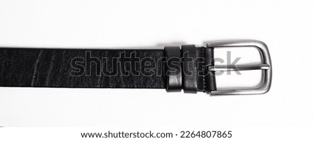 Black leather belt for trousers and jeans. Fastened fashionable men leather belt with dark chrome matted metal buckle isolated on white background. Male accessory. Luxury strap. Haberdashery goods.