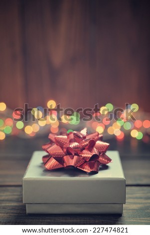 Silver gift box with red bow over wooden background
