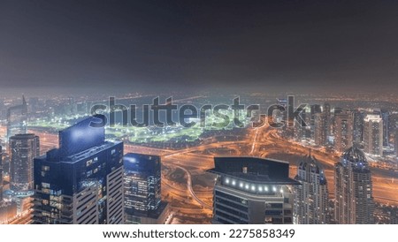 Panorama of Dubai Marina with JLT skyscrapers and golf course night , Dubai, United Arab Emirates. Aerial view from above towers. City lights illumination