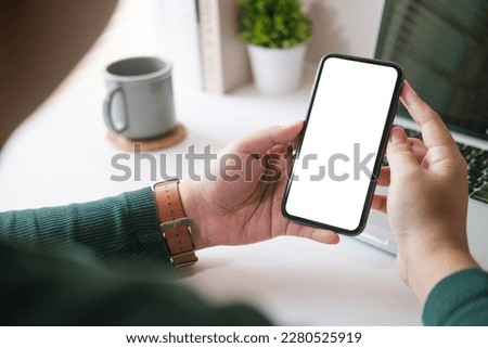 Man freelancer using smart phone at home office desk. Blank  screen for your text message or information content.