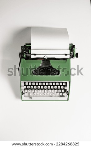 Vintage green typewriter on a white background. Retro typewriter with a sheet of paper. 
