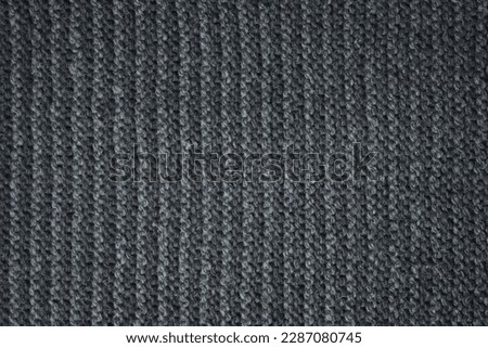 Black striped knitted fabric. Dark knitted texture background.