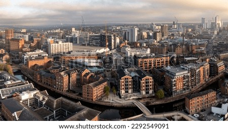 An aerial panoramic view of luxury waterfront apartments along Brewery Wharf on the Leeds to Liverpool canal in a Leeds cityscape skyline at sunrise